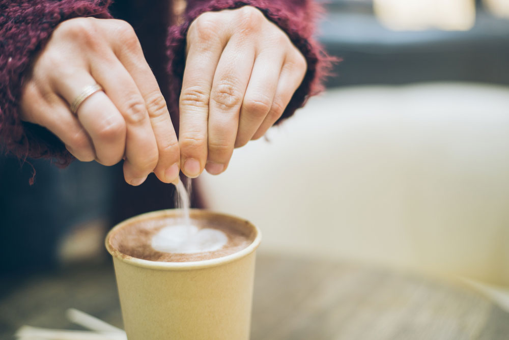 woman pouring powder into coffee cup