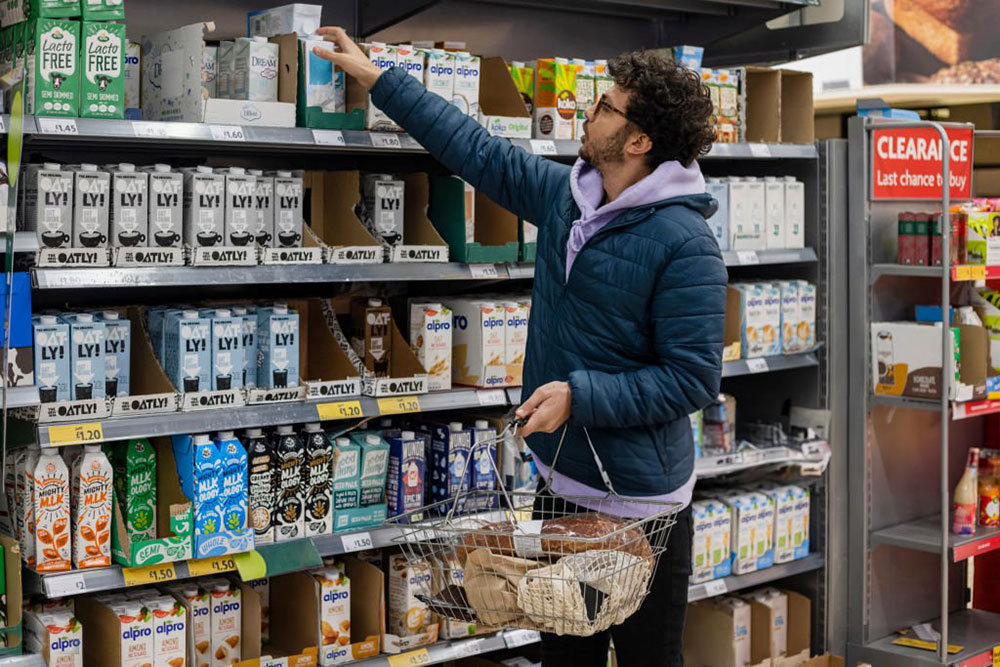 A man is shopping in the store for liquid creamers.