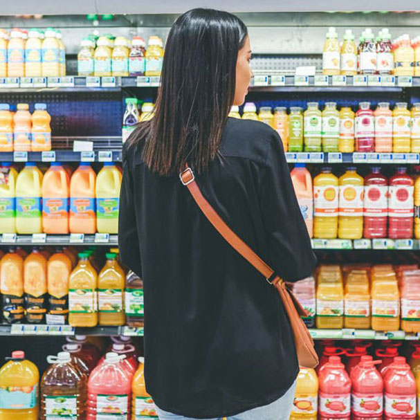 A woman standing in front of shelves filled with juice.